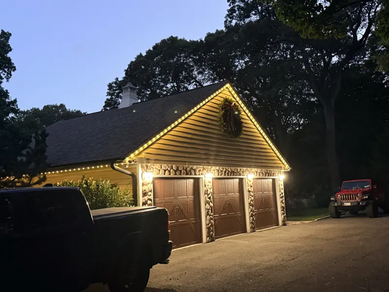 Permanent outdoor lighting on Long Island by North Star: warm white soffit lighting over a three-car garage